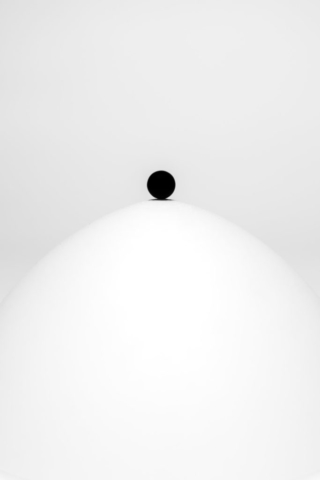 A black sphere on a white dome, gradually rolling down. At a glance, they seem perfect abstractions, but closer inspection reveals the rough texture and imperfection of real objects, actually existing.