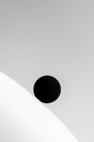 A black sphere on a white dome, gradually rolling down. At a glance, they seem perfect abstractions, but closer inspection reveals the rough texture and imperfection of real objects, actually existing.